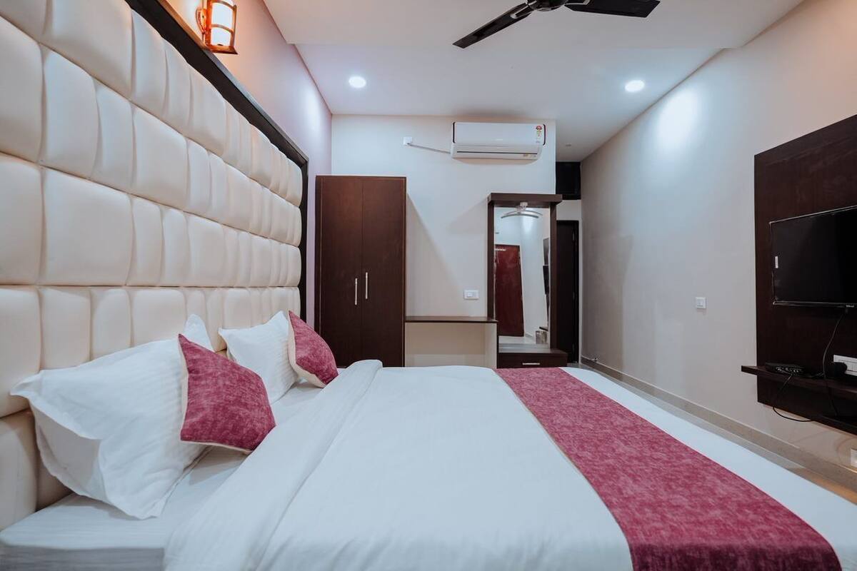 Een moderne hotelkamer met een groot bed, een kledingkast, een airconditioningsunit en een televisie aan de muur.