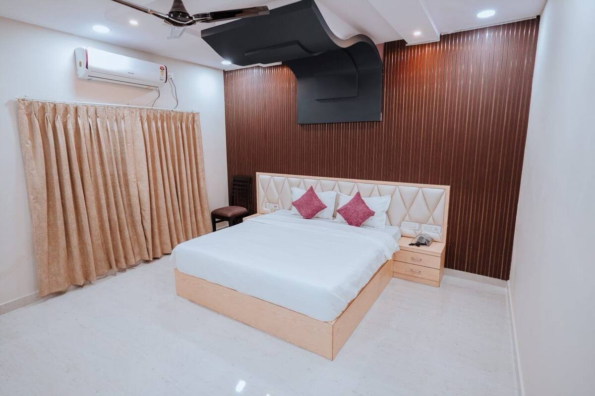 Een slaapkamer met een bed, nachtkastje en een wandairconditioner.