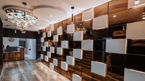 Un vestíbulo de hotel moderno con suelo de madera, una recepción y una lámpara decorativa.