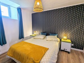 A modern bedroom with a large bed, two bedside tables with lamps, a window with curtains, and a wall with a starry pattern.