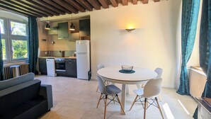 A modern kitchen with a dining area, including a round table with chairs and a sofa. - Historic 2BR Cottage with Modern Amenities & Shared Pond in Brenne Park (Communauté de communes Brenne - Val de Creuse-Douadic)