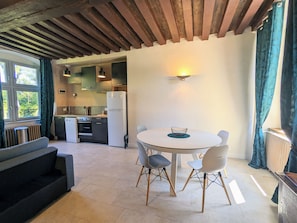A modern kitchen with a dining area, including a round table with chairs and a sofa. - Historic 2BR Cottage with Modern Amenities & Shared Pond in Brenne Park (Communauté de communes Brenne - Val de Creuse-Douadic)