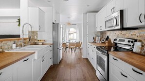 Eine moderne Küche mit weißen Schränken, einer Holz Arbeitsplatte, einem eingebauten Ofen und einer Mikrowelle.