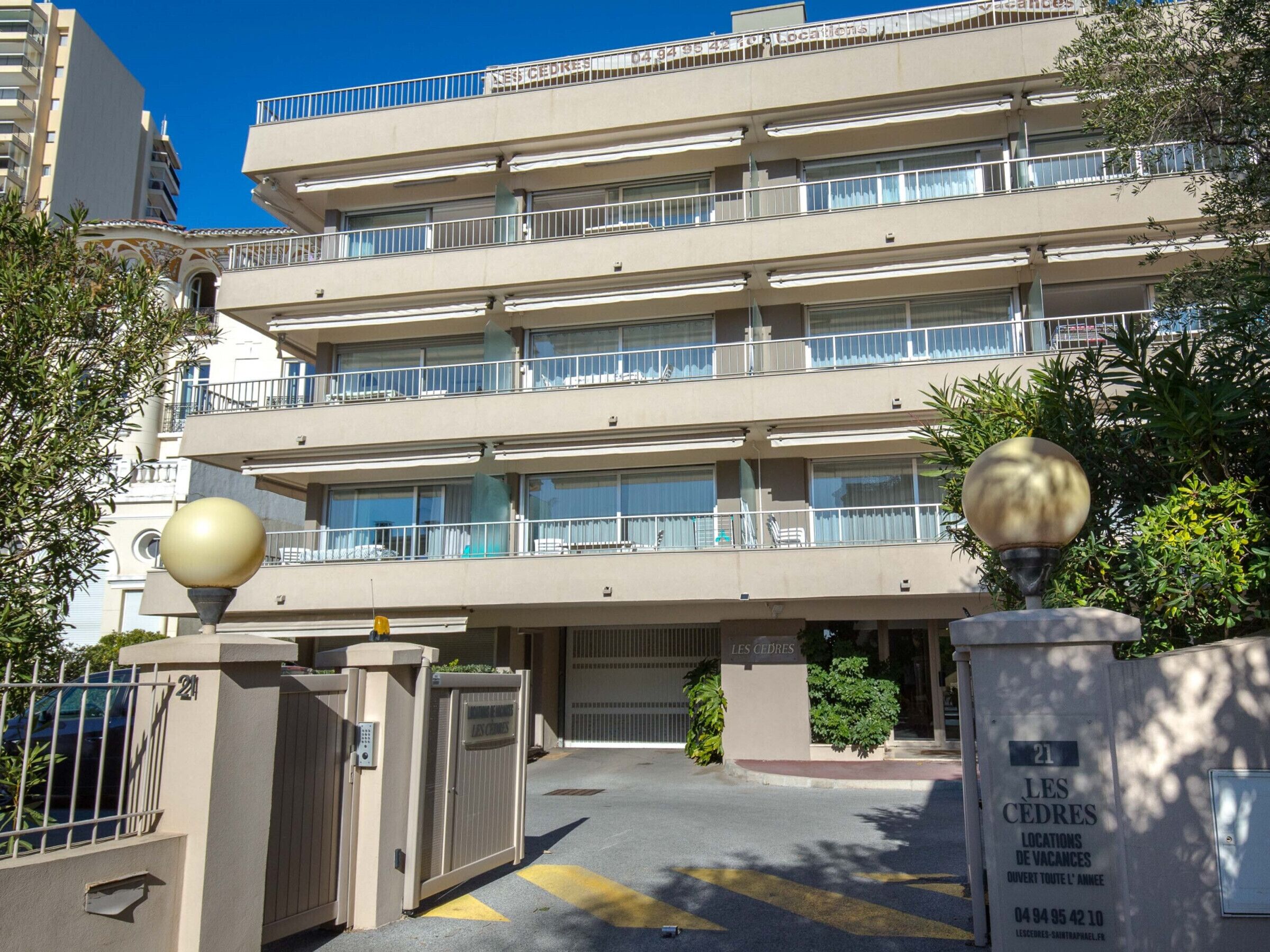 A multi-story hotel with balconies, a gated entrance, and a sign indicating availability.