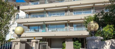 A multi-story hotel with balconies, a gated entrance, and a sign indicating availability.