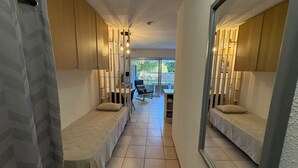 A corridor with two single beds, wooden walls, and a view of an outdoor patio area. - Beachside Studio - AC, Balcony, Near Shops & Casino, Free WiFi - Perfect Location! (Saint-Raphaël)