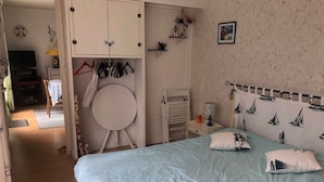 Ein Schlafzimmer mit einem Bett, einem runden Spiegel, einem Kleiderschrank und einem Nachttisch.