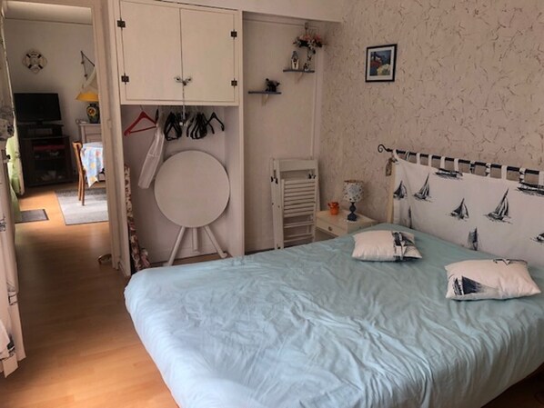 Un dormitorio con cama, espejo redondo, armario y mesita de noche.