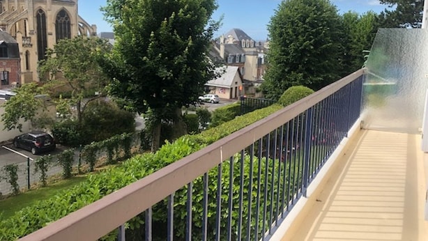 Ein Balkon mit Blick auf eine Kirche und umliegendes Grün.