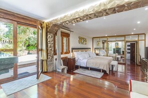Ruime slaapkamer met een groot bed, een zithoek met een tafel en stoelen, en uitzicht op de omgeving.