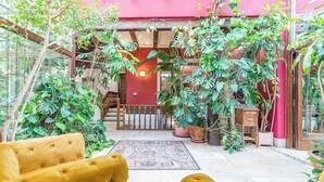 A cozy indoor space with a yellow sofa, a staircase, and lush green plants.