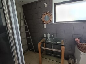 A bathroom with a glass sink, dark tiled walls, a wooden ladder, a decorative mirror, and a window. - Gîte Pays Bigouden Pouldreuzic: Country House Near the Sea - Sleeps 4 (POULDREUZIC)