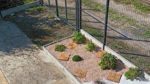A staircase leading to a garden area with a metal fence, gravel paths, and wooden planters. - THE HOLIDAYS (Arques)
