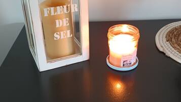 Una vela en un tarro de cristal sobre una mesa negra, junto a una caja blanca con texto.
