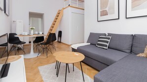 Un salon moderne avec un canapé gris, une table basse en bois et un escalier menant à un niveau supérieur.