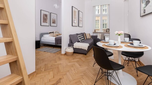 Un salon moderne avec un canapé gris, une table à manger avec des chaises et un escalier.
