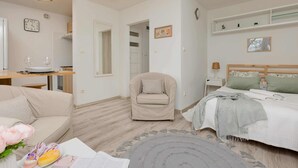 A modern bedroom with a bed, a chair, a sofa, a small table, and a bedside table. - Bright Studio with Balcony | Tranquil Zoliborz (Warszawa)