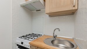 A kitchen with a gas stove, oven, and stainless steel sink. - Bright Studio with Balcony | Tranquil Zoliborz (Warszawa)