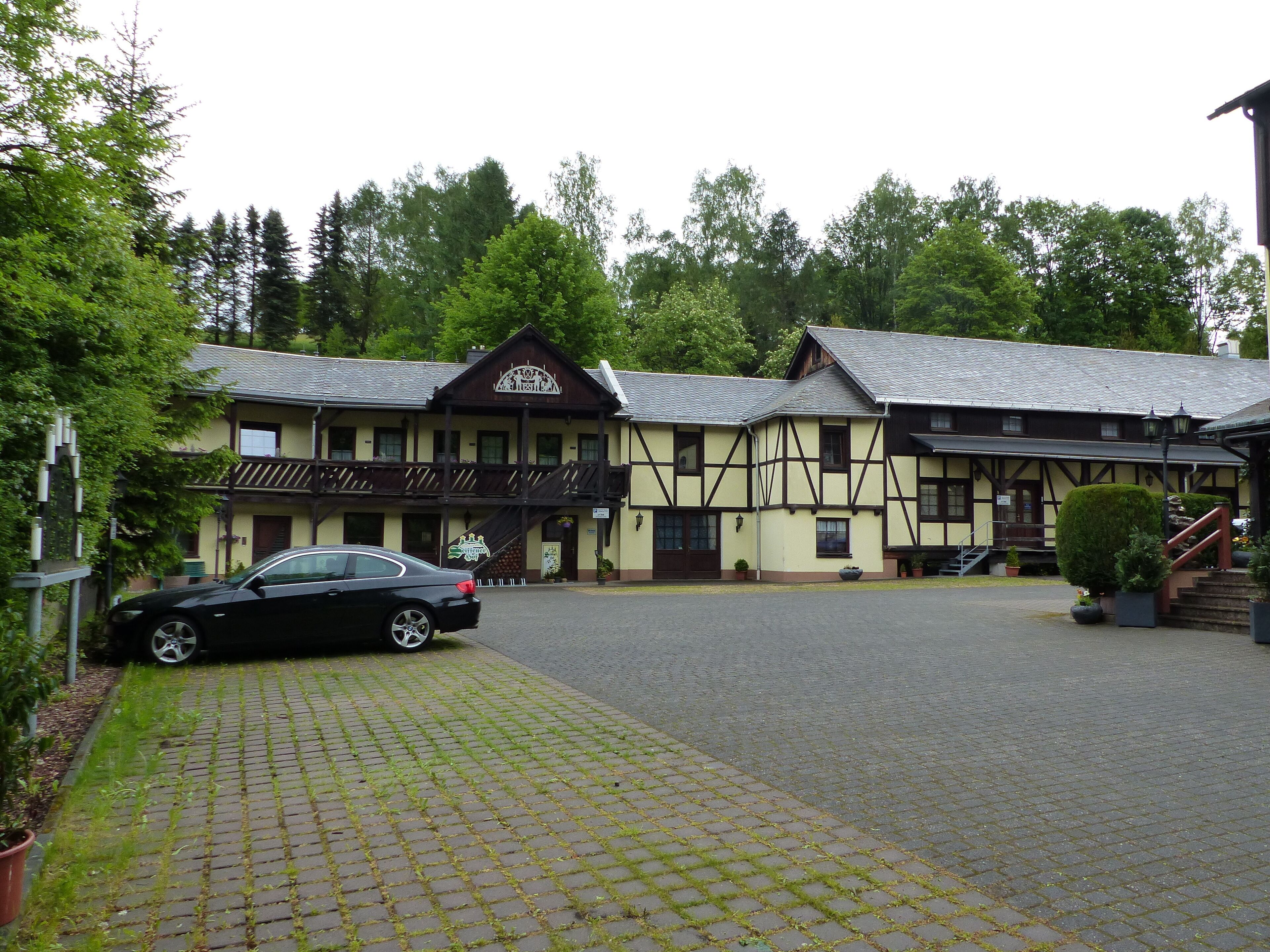 Ein traditionelles Gebäude mit einem zentralen Eingang, einer Treppe zum Haupteingang und einem gepflasterten Zugangsweg.