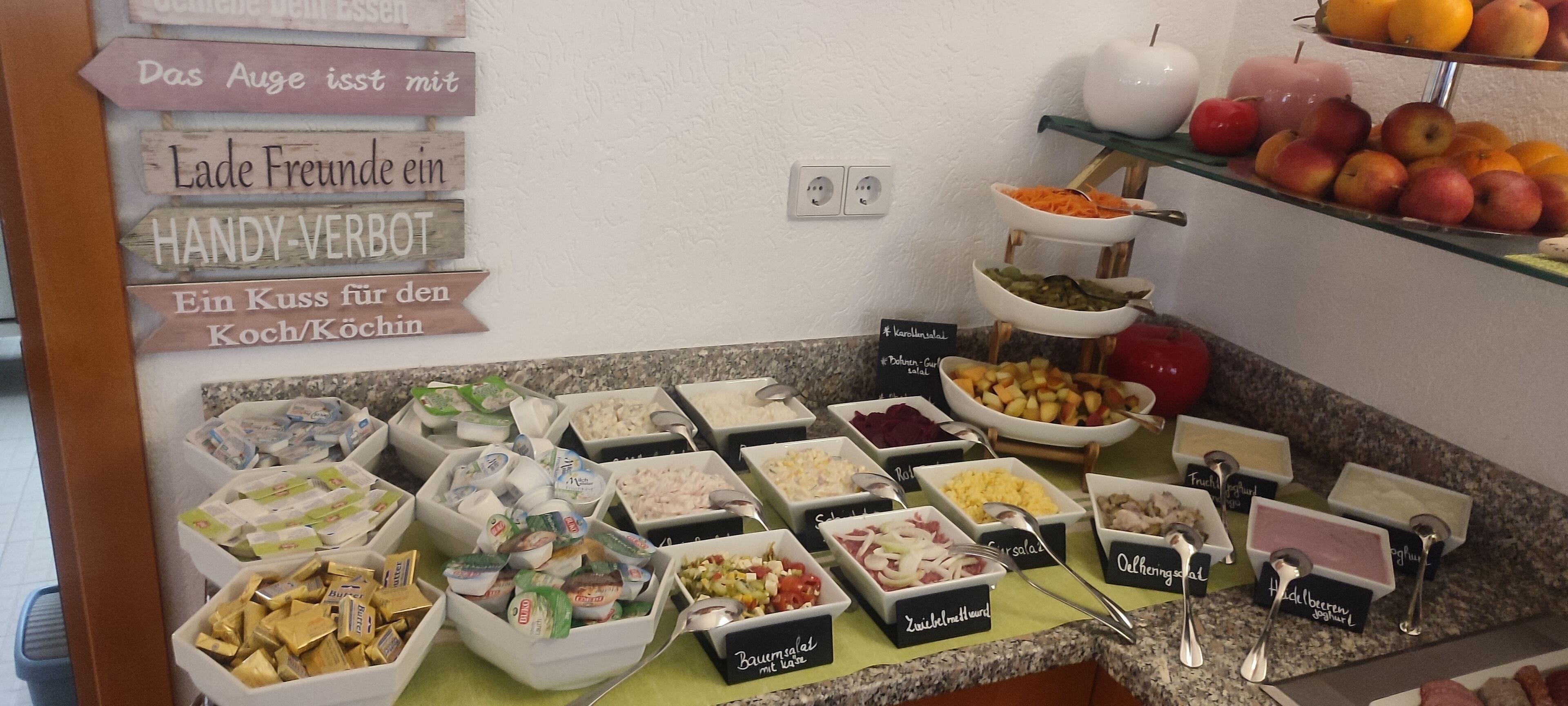A buffet with various food items and a sign with German text.