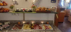 Un bufé con diversas opciones de comida y una presentación iluminada con velas.