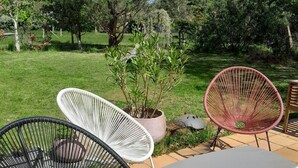 A patio area with outdoor furniture including a table and three chairs, surrounded by a grassy lawn and trees. - Messanges - Landes: Villa Waves & Olas (Messanges)