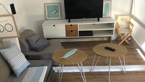A modern living room with a sofa, two small tables, a TV, and a wooden floor. - Messanges - Landes: Villa Waves & Olas (Messanges)