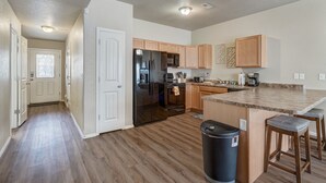 Una cocina moderna con armarios de madera, un refrigerador de acero inoxidable, un microondas y una cafetera.