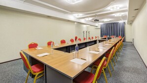 A conference room with a long table, red and yellow chairs, and ceiling lights. - Hotel Touristan Bishkek (Bishkek)