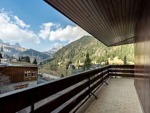Un balcon offrant une vue sur un paysage montagneux, un bâtiment en bois et une église.