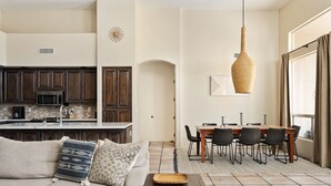 A spacious living area with a sofa, a dining table with chairs, and a kitchen with dark wooden cabinets and a microwave. - Private Desert Sanctuary with Pool, Spa, & Putting Green (Cave Creek)