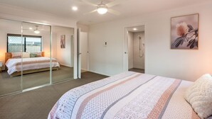Ein Schlafzimmer mit einem großen Bett, einem begehbaren Kleiderschrank, einer Dusche und einem Deckenventilator.