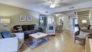 A spacious living room with a ceiling fan, a dining area, and a staircase.