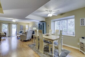 A spacious living room with a dining area, a ceiling fan, and large windows. - Luxury 2 BR 2.5 BA vacation townhome in Shipyard Bikes & Beach Gear included (Hilton Head Island)