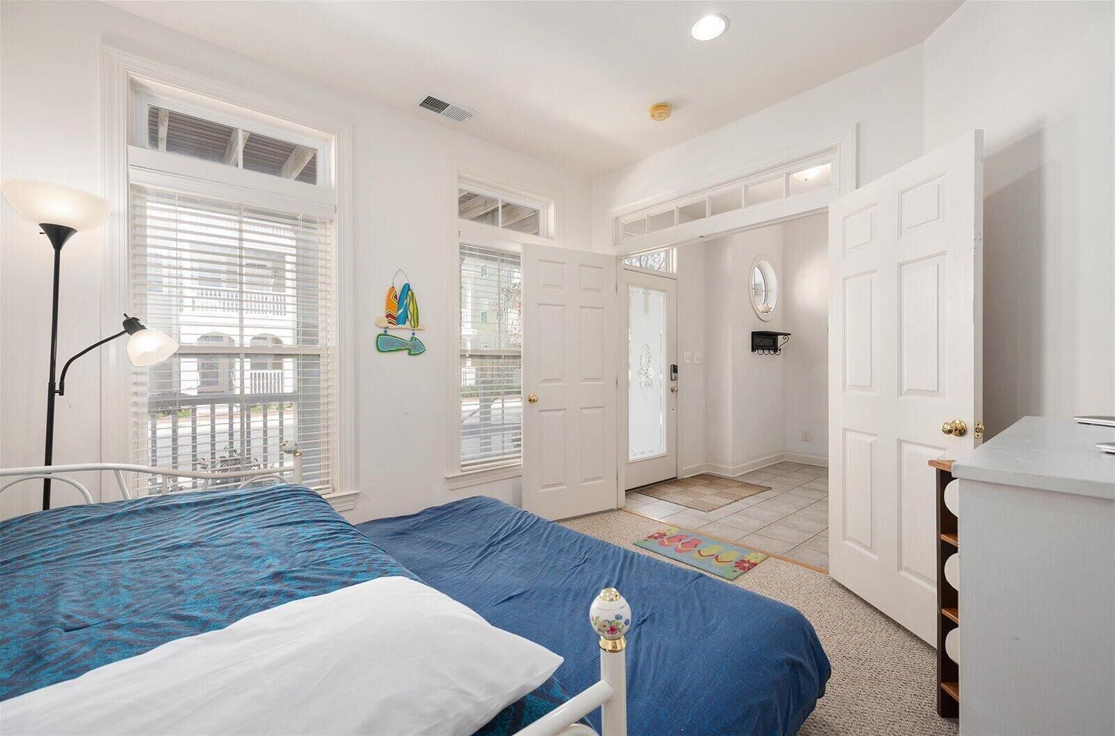 A bedroom with a bed, a nightstand, a lamp, and a dresser.