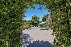 A courtyard with a paved patio, outdoor seating, and a building in the background.