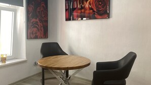 Une salle de réunion moderne, dotée d’une table ronde en bois, de deux chaises noires et de deux grandes peintures florales accrochées aux murs.
