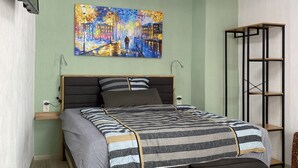 Une chambre moderne avec un lit, un tableau, une télévision et un plancher en bois.