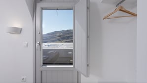 A white door with a view of a mountainous landscape. - Golden View Jacuzzi Suites (Santorini)