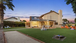 Una casa con patio, césped y mobiliario exterior.