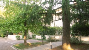 Ein gepflasterter Weg mit Bäumen und einem weißen Gebäude im Hintergrund.