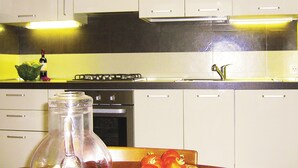 Eine Küche mit weißen Schränken, einem Gasherd, einer Spüle und einer Weinflasche.
