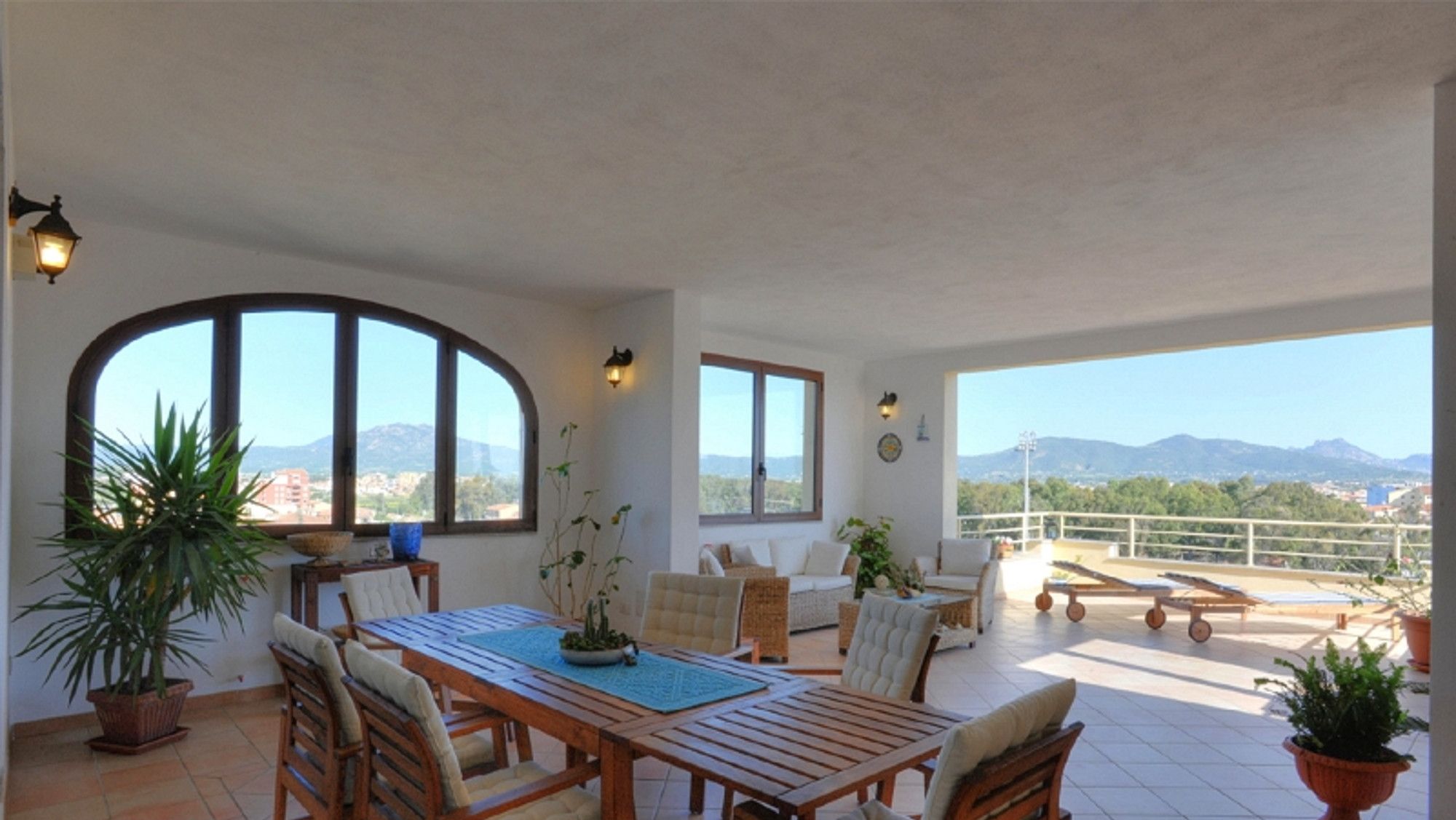 Une pièce spacieuse comprenant un coin repas, un canapé et un balcon offrant une vue sur les montagnes.