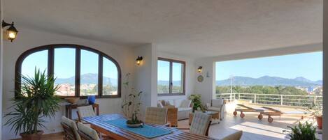 Une pièce spacieuse comprenant un coin repas, un canapé et un balcon offrant une vue sur les montagnes.