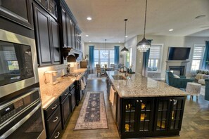 A modern kitchen with dark cabinetry, stainless steel appliances, and a central island. - Coastal Club * 18353 * NEW Exceptional Lewes Beach House (Lewes)