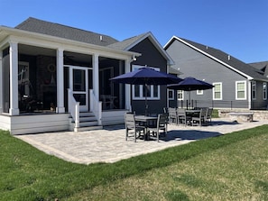 A covered patio with outdoor furniture and a stone pathway.