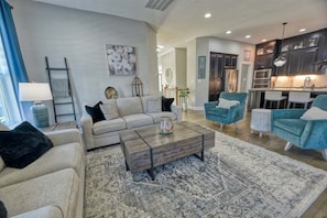 A spacious living room with a sofa, coffee table, and blue armchairs.