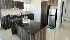 Una cocina moderna con armarios de madera oscura, una isla central, electrodomésticos de acero inoxidable y un ventanal que proporciona luz natural.
