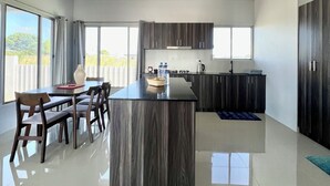 Una cocina moderna con armarios de madera oscura, una isla central y un comedor con sillas.