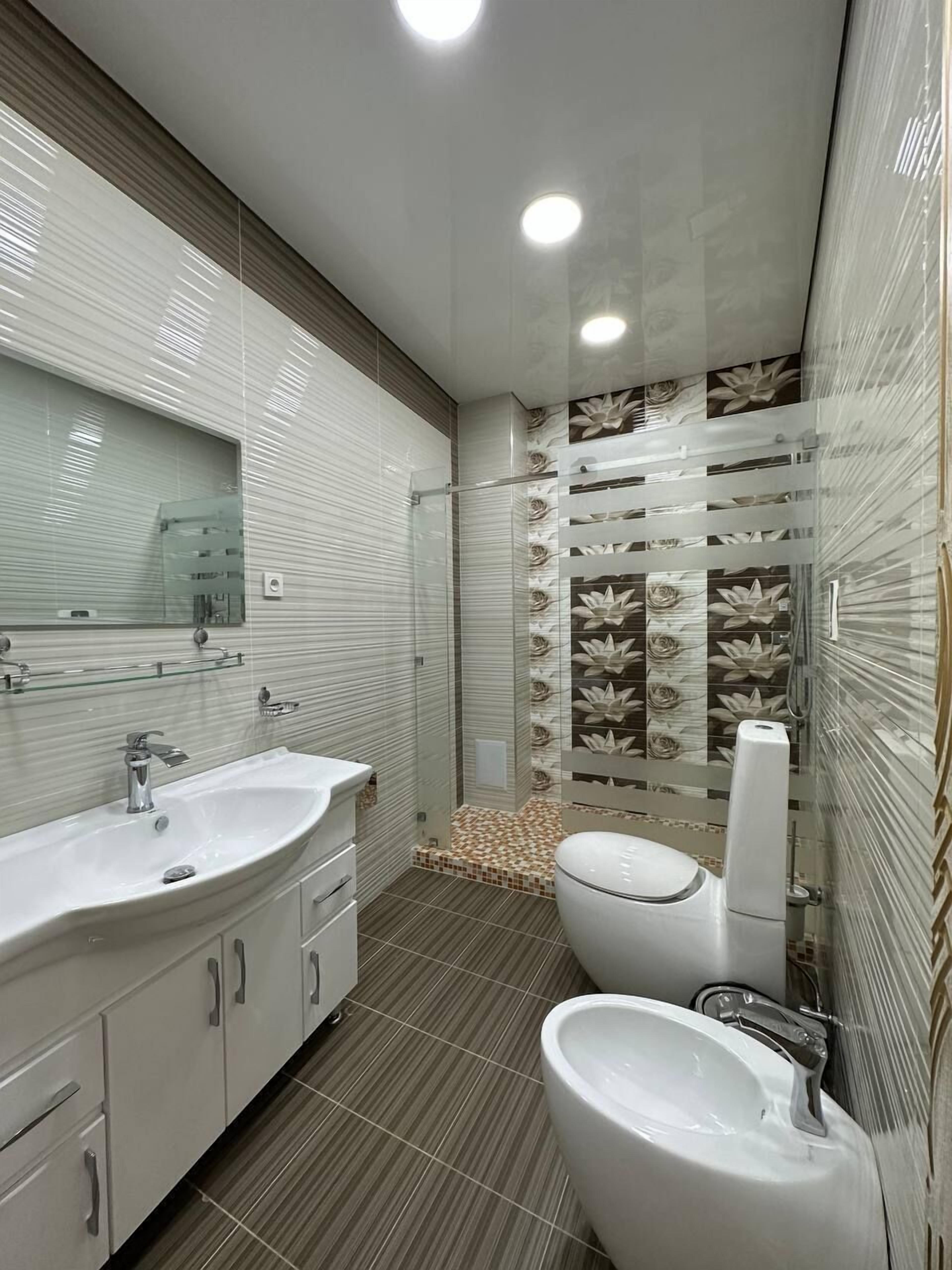 Un baño moderno con un espejo grande, dos lavamanos, un inodoro y un bidé.